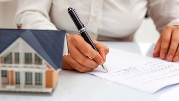Women signing documents with model home